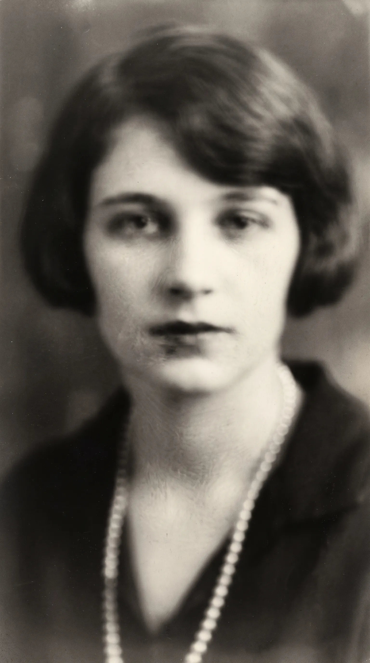 Heavily blurred 1920s close-up portrait of a young woman with a bob haircut and pearls