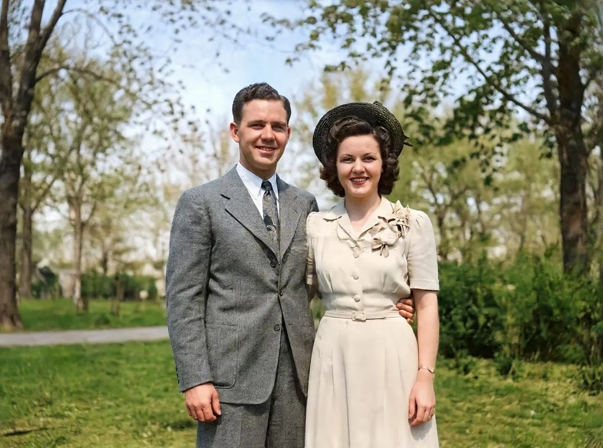 The same couple restored and colorized by Retrocap, the man in a grey suit and the woman in a cream dress and straw hat